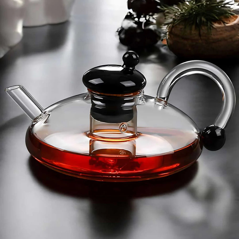 Elegant borosilicate glass teapot pouring herbal tea into matching cup