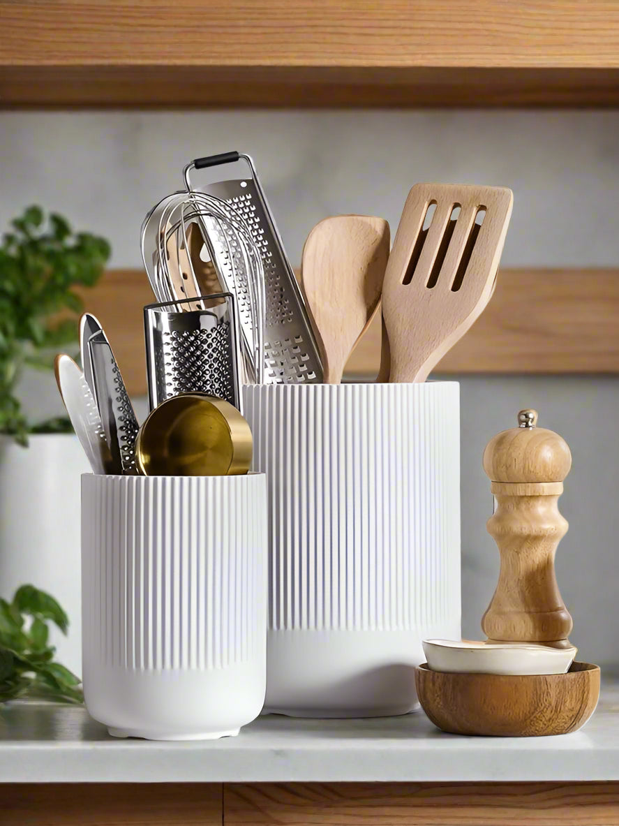 White kitchen utensil holder with various utensils on a tiled wall background